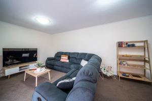 uma sala de estar com um sofá azul e uma televisão em Escape to Adelaide Hills 