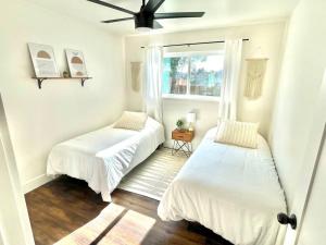 two beds in a white room with a window at Peaceful Canyon Retreat in San Diego