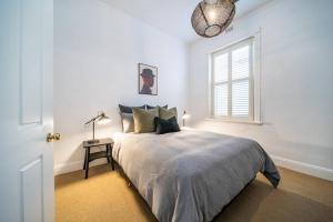 a white bedroom with a bed and a window at Netley Cottage Eastwood in Rose Park