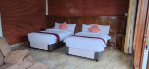 Duas camas com lençóis brancos e almofadas laranja num quarto em The Mungseng Villa Bali em Singaraja
