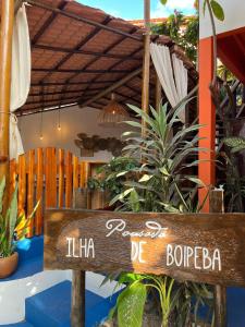 un panneau en bois devant un bâtiment avec des plantes dans l'établissement Pousada Ilha De Boipeba, à Île de Boipeba