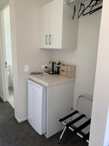 a small kitchen with white cabinets and a chair at The Matarangi B & B in Matarangi