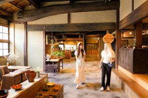 Kokuryō的住宿－古民家オーベルジュmocca，两个女人站在一个房间里,头上有一个篮子