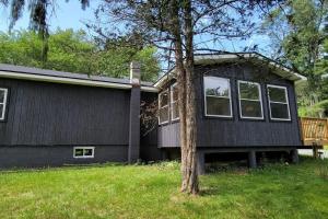 a black house with a tree in front of it at Bethel Woods Cabin in Mongaup Valley