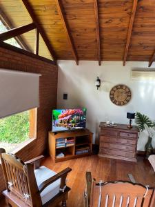 sala de estar con TV y techo de madera. en Cabaña Las dos Marías en Sierra de los Padres