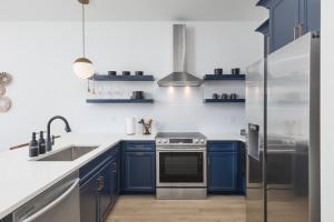 a kitchen with blue cabinets and a stainless steel refrigerator at Modern East Nashville Condo 3 Miles to Downtown in Nashville +38 photos
