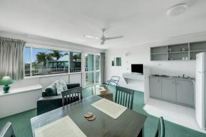 a living room with a dining table and a kitchen at Reef Adventureland Motor Inn in Tannum Sands