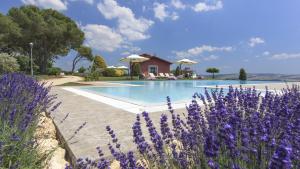 a pool with purple flowers in front of a house at Locanda Rossovino in Montebello