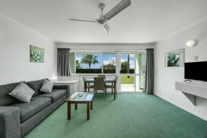 een woonkamer met een bank en een tafel bij Reef Adventureland Motor Inn in Tannum Sands