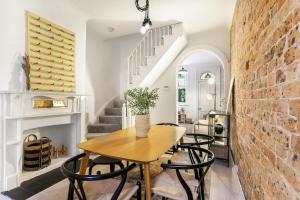 a dining room with a table and chairs and a brick wall at Surry Hills l 2 Bedroom Terrace Home in Sydney
