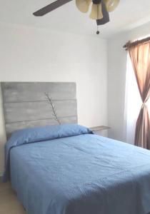 um quarto com uma cama azul e uma ventoinha de tecto em Casa cómoda para descansar o vacacionar em Xochitepec
