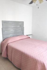 uma cama com um edredão rosa num quarto em Casa cómoda para descansar o vacacionar em Xochitepec