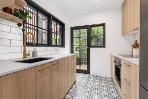 a kitchen with wooden cabinets and a black and white tile floor at Ultimo l Renovated 2 Bedroom House With Rooftop Balcony in Sydney