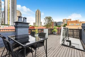 a wooden deck with a table and chairs on a balcony at Ultimo l Renovated 2 Bedroom House With Rooftop Balcony in Sydney