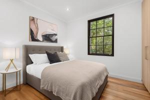 a white bedroom with a bed and a window at Ultimo l Renovated 2 Bedroom House With Rooftop Balcony in Sydney