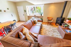 a living room with a brown leather couch and a wood stove at Sua Casa em Canela in Canela