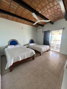 a bedroom with two beds and a ceiling fan at HOTEL VILLAS EL DORADO in Rincon de Guayabitos