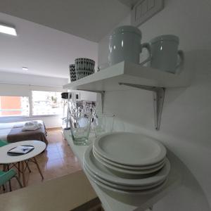 une cuisine blanche avec une pile de plaques sur un comptoir dans l'établissement Calle 10 - Monoambiente, à La Plata