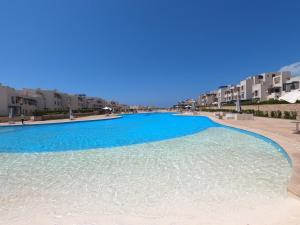 een groot zwembad met blauw water voor de gebouwen bij Remas resort in El Alamein