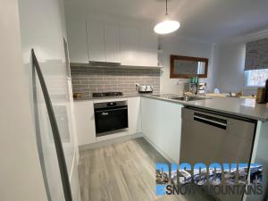 a kitchen with white cabinets and a stove top oven at Three Bears 2 in Thredbo