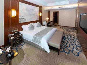 YunRay Hotel Shijiazhuang في هيبي: غرفة نوم بسرير كبير وتلفزيون بشاشة مسطحة