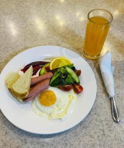 um prato de comida de pequeno-almoço com ovos, salsichas e legumes e um copo de sumo em Sunjin Grand Hotel em Ulan Bator