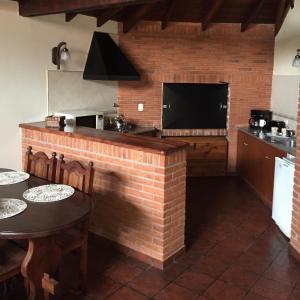 uma cozinha com uma parede de tijolos com uma mesa e uma televisão em Cabaña Las dos Marías em Sierra de los Padres