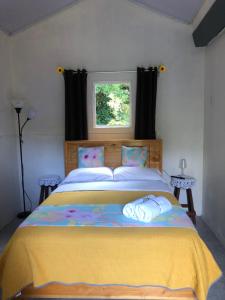 a bedroom with a bed with a yellow blanket and a window at Lissadell Country House in Monteverde Costa Rica