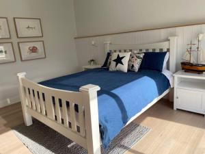 a bedroom with a white bed with blue sheets and pillows at Windspray Cottage in Port Albert