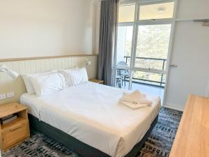 a bedroom with a bed and a large window at Pippi's at the Point in Warners Bay