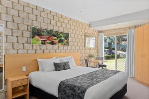 a bedroom with a bed and a brick wall at Great Divide Motor Inn in Toowoomba