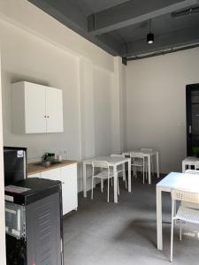 eine Küche mit weißen Tischen und Stühlen sowie weißen Schränken. in der Unterkunft PassGo Thamrin in Jakarta