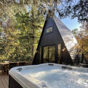 una casa negra con una bañera delante en Sundance A-Frame 5 Min Walk to Resort & XL Hot Tub, en Sundance