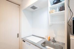 eine Küche mit einer Spüle und einer Mikrowelle in der Unterkunft AZEST-RENT Haneda 11 in Tokio