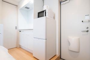 Zimmer mit einem weißen Kühlschrank und einem Schrank in der Unterkunft AZEST-RENT Haneda 11 in Tokio