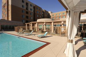 a swimming pool with two chairs and a umbrella at Residence Inn Phoenix Desert View at Mayo Clinic in Phoenix