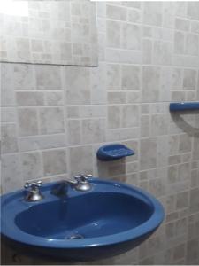 um lavatório azul numa casa de banho com uma parede em azulejo em Hostal El Farolito em Humahuaca