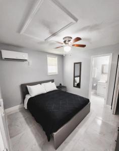 um quarto com uma cama preta e uma ventoinha de tecto em Cozy Cottage em Tampa