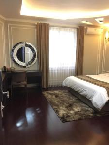 a bedroom with a bed and a desk and a mirror at Holiday Hotel in Hai Phong