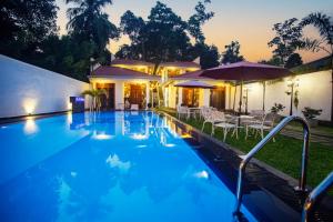 a swimming pool with chairs and umbrellas in front of a house at Superresidence in Balapitiya