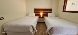 2 camas en una habitación con una lámpara en una mesa en Hotel La Posada de Francisca, en Písac
