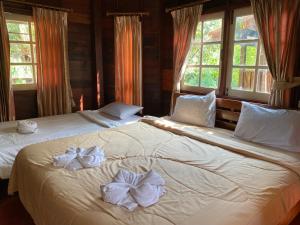 a bedroom with two beds with bows on them at สวนดวงมณี รีสอร์ท in Ban Tha Thong Mon