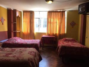 a hotel room with two beds and a window at Puno Wasi Hotel in Puno