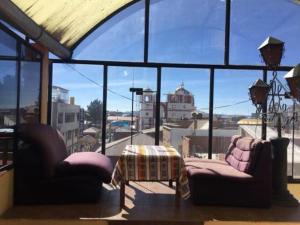 a balcony with two chairs and a view of a city at Puno Wasi Hotel in Puno