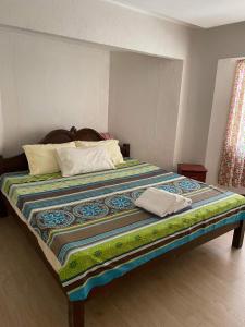 a large bed with a colorful quilt on it at Villas de piscina in Sipalay