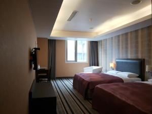 a hotel room with two beds and a window at Metropolis Hotel in Taoyuan