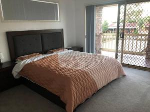 a large bed in a bedroom with a balcony at Waterfront Luxury 4 bed Home walking to Broadwater in Gold Coast