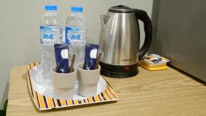 a tray with cups and bottles of water on a table at DonMueang station hostel in Ban Don Muang (1)