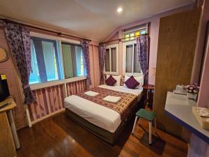 a bedroom with a bed and a desk and windows at Samsen Sam Place in Bangkok