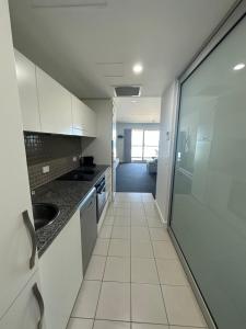 a kitchen with white cabinets and a large glass door at Absolute Beachfront at the Pier Glenelg in Adelaide